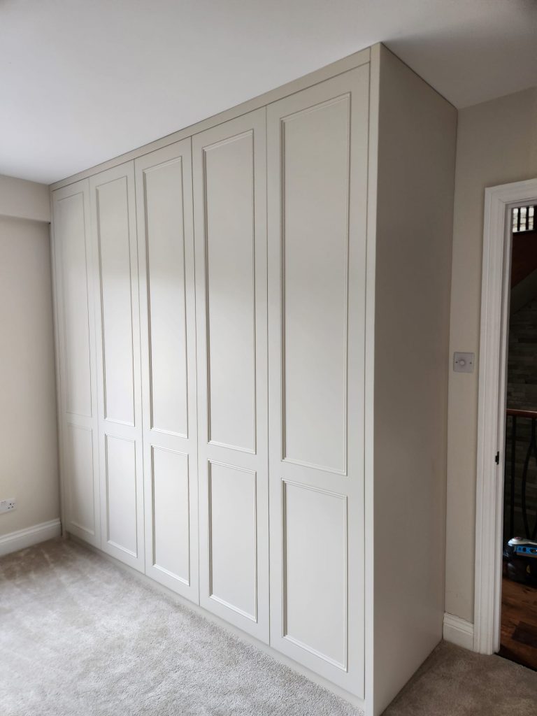 Floor-to-ceiling bespoke wardrobe with oak interiors and LED lighting in Surrey home